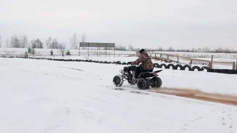 The guy is riding an ATV on a snow-covered road in winter Stock Footage 84955344