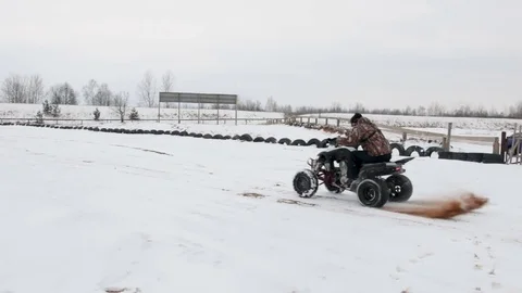 The guy is riding an ATV on a snow-covered road in winter Stock Footage 84955468