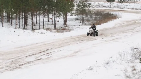 The guy is riding an ATV on a snow-covered road in winter Stock Footage 84957160