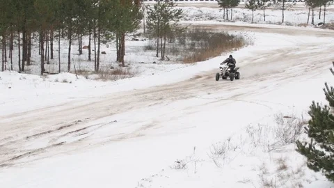 The guy is riding an ATV on a snow-covered road in winter Stock Footage 84957546