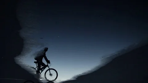 The guy is riding a bicycle. The silhouette is reflected in the water. Stock Footage 77726761