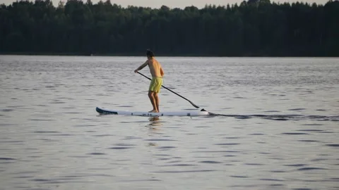 The guy is rowing with an oar standing on a swimming board Stock Footage 204960416