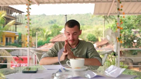 The guy rubs his face with his hands. He takes a pen and takes notes. Video stock 231336719