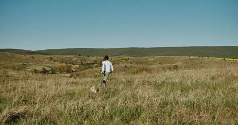 Guy running with a dog on the grass.  Stock Footage 153879790