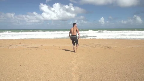 Guy Running Down the Beach Towards the Ocean Stock Footage 79277455