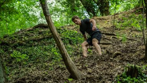 The guy is running down a steep hill while participating in an ocr race Stock Photos