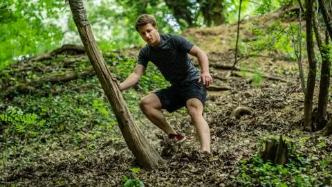 The guy is running down a steep hill while participating in an ocr race Stock Photos