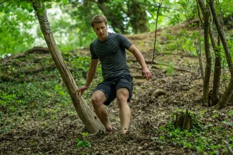 The guy is running down a steep hill while participating in an ocr race Stock Photos