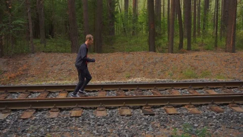 The guy runs along the rails in the forest. Stock Footage 93975252