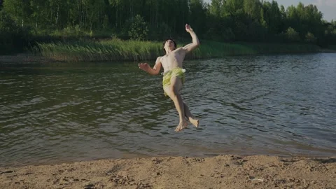 The guy runs along the shore and jumps into the water Stock Footage 248524698