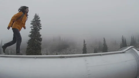 The guy runs through a big pipe in the mountains Stock Footage 107813188