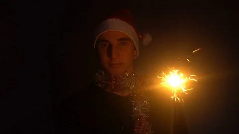 A guy in a Santa hat holding in his hand a glittering Sparkler Stock Footage 82730894