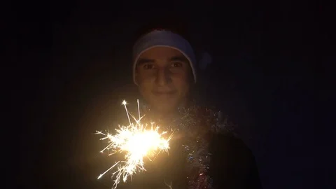 A guy in a Santa hat holding in his hand a glittering Sparkler Video stock 82731087