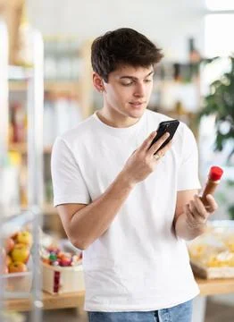Guy scanning QR code on bottle of red pepper with phone Stock-Fotos