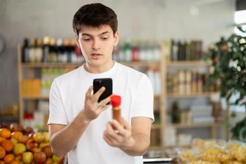 Guy scanning QR code on bottle cardamom label in grocery department of Foto stock