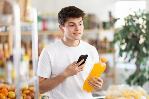 Guy scanning QR code on soft drink bottle in supermarket Foto stock