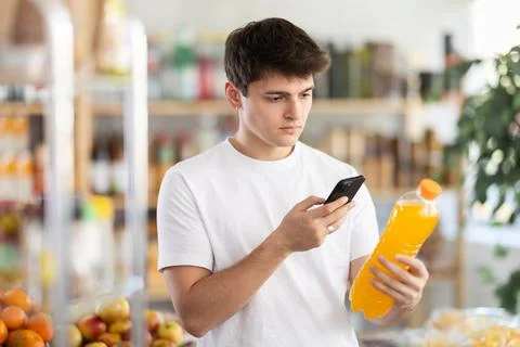 Guy scanning QR code on soft drink bottle in supermarket Stock-Fotos