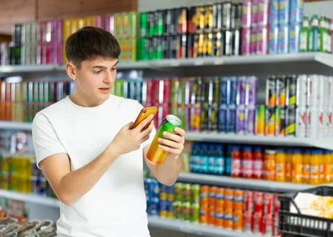 Guy scans bar code from label of an aluminum can with drink in grocery 写真素材