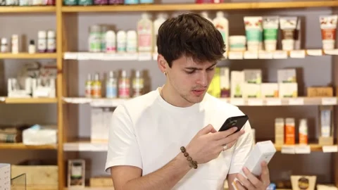 Guy scans the barcode of a package of food supplements in an eco supermarket on 動画素材 341378409