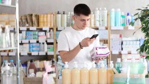 Guy scans the barcode of a package of pads in a pharmacy. Young man takes a Stock Footage 320923429