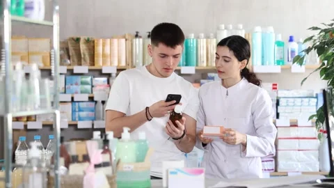 Guy scans QR code on box cough syrup label. Female pharmacist offers various Stock Footage 314760833