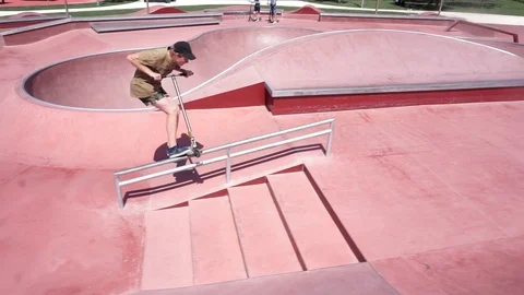 Guy on the scooter slides on the railing and jumping in skate park Stock-Footage 102249104