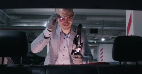 Guy searches in car trunk for tools for changing tires Stockbeeldmateriaal 294606779