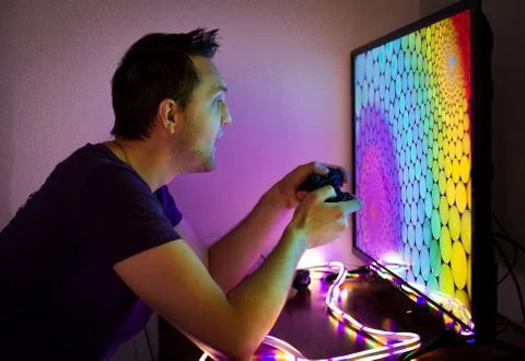 Guy with a set-top box sitting at the big color TV screen in the dark Stock Photos