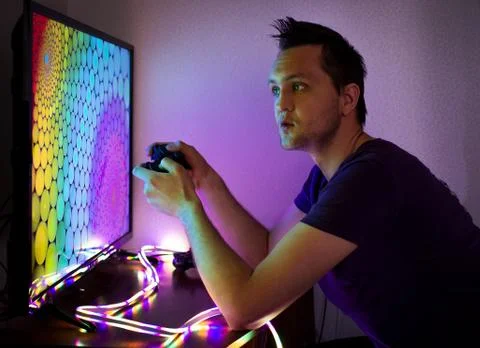 Guy with a set-top box sitting at the big color TV screen in the dark Stock Photos