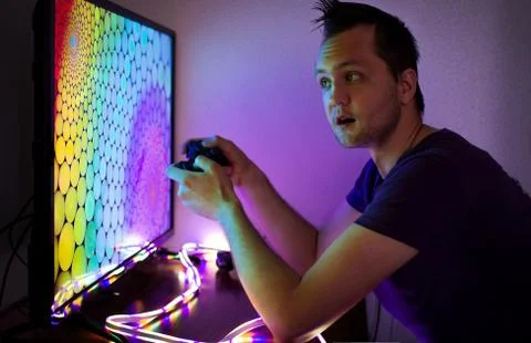 Guy with a set-top box sitting at the big color TV screen in the dark Stock Photos
