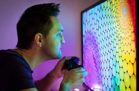 Guy with a set-top box sitting at the big color TV screen in the dark Stock Photos
