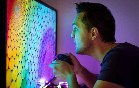 Guy with a set-top box sitting at the big color TV screen in the dark Stock Photos