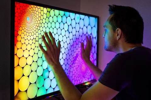 Guy with a set-top box sitting at the big color TV screen in the dark Stock Photos