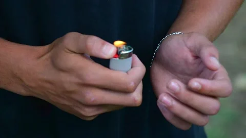A guy sets fire to a lighter in his hands close-up Stock Footage 228665393