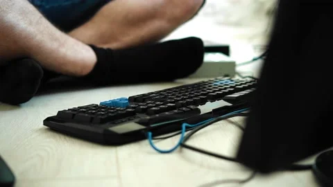 The guy is setting up a PC sitting in front of the monitor on the floor Video stock 213724493