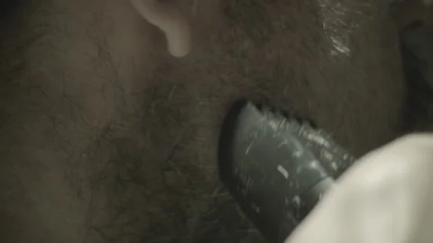 The guy shaves his beard with a trimmer in front of the bathroom mirror. Close Stock Footage 131464873