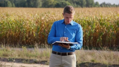 A guy in a shirt looks at a book on the background of the field. Bible Stock Footage 141118083