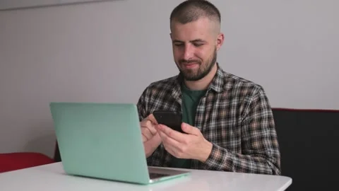 The guy in the shirt is talking on the phone working on the computer, working Stock Footage 190020838