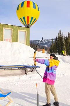 The guy shoots sharp arrows from a bow, against the background of a bright .. Stock Photos