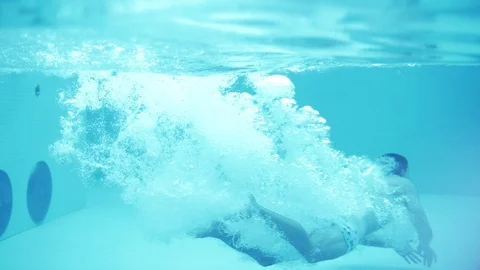 The guy in the shorts jumps into the pool with clear water. Slow motion Stock Footage 102652401