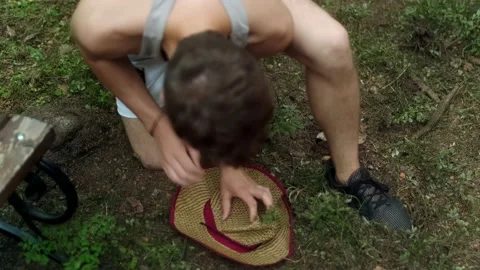 A guy in shorts jumps on a straw hat lying on the ground. Stock Footage 197480356