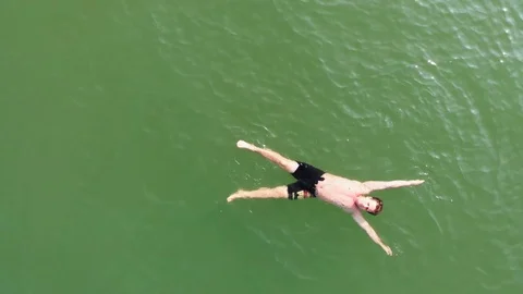 A guy in shorts swims on his back in sea. Top view. Aerial shot. Stock Footage 126859262