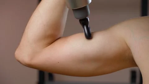 The guy shows his biceps and massages it with a percussion massager, close-up Stock Footage 276766484