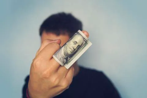 Guy shows the middle finger on which are wound 100 dollar banknote of America Stock Photos
