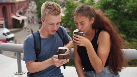 Guy shows something to his girlfriend on smartphone screen at city street Stock Footage 93005182
