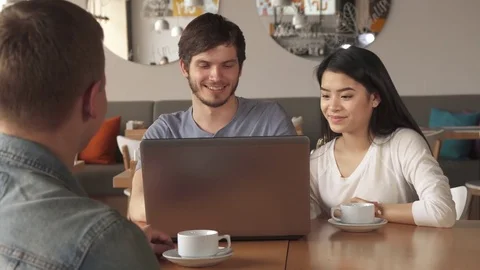 Guy shows something on laptop to his friend at the cafe Stock Footage 74305562