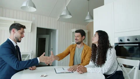 Guy signing housing contract getting key from realtor hugging happy wife indoors Stock Footage 157307299