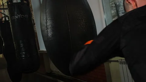 Guy simulates real fight working with big punching bag in hall Stock Footage 306664482