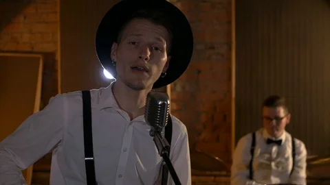 The guy is singing and playing guitar at the studio. The music band plays Stock Footage 111066692