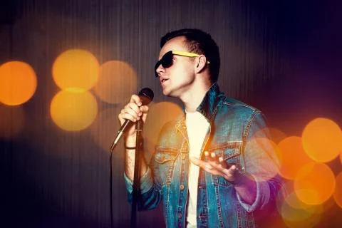 Guy Singing with Microphone. Bokeh Background. Stock Photos